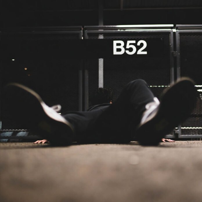 Exhausted traveler slumped on airport floor near gate B52.