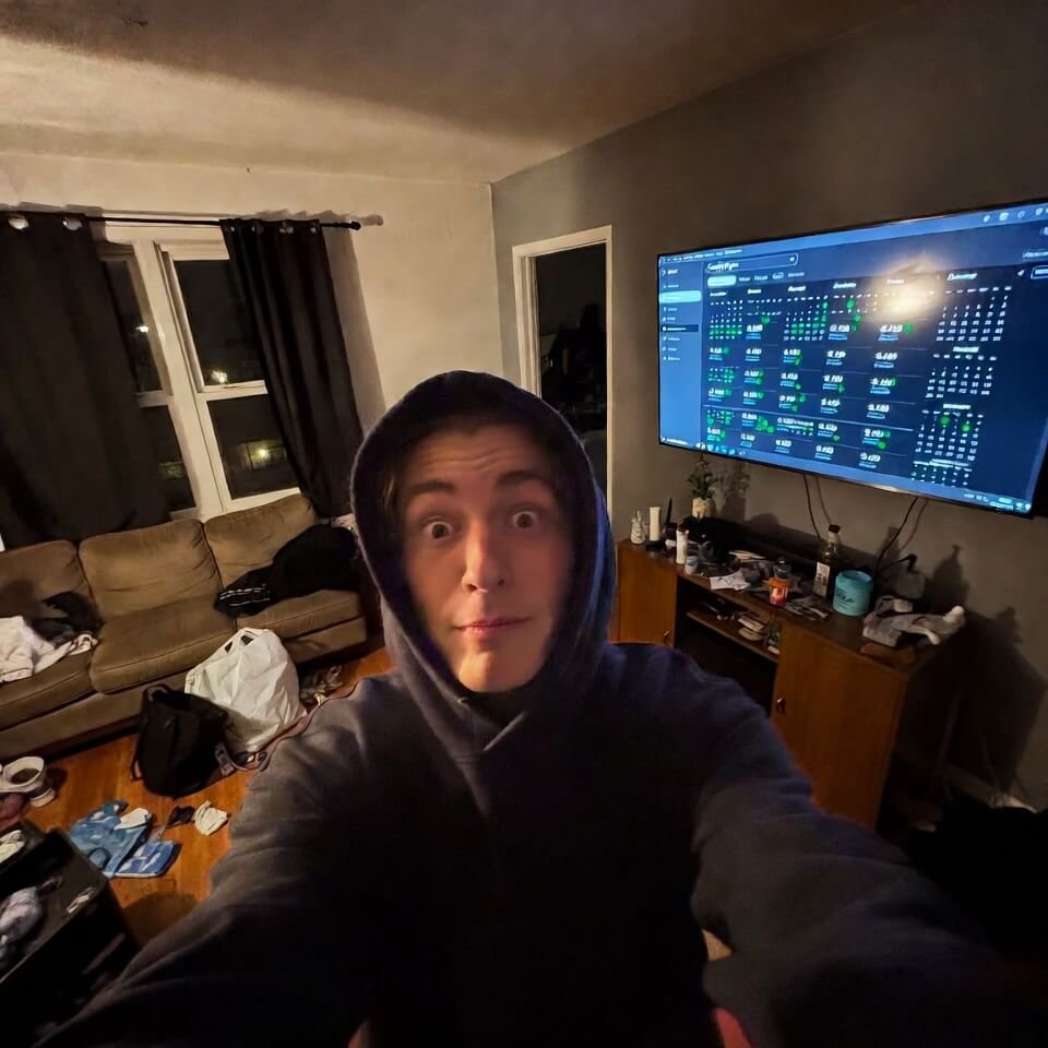 Excited-deranged 2 a.m. hoodie selfie with Google Flights calendar reflection.