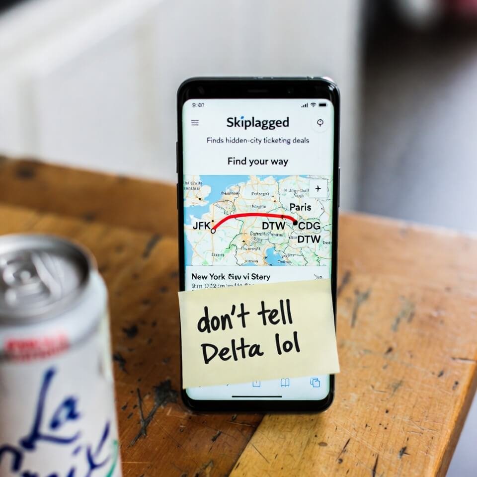 Phone showing Skiplagged hidden-city map with "don’t tell Delta lol" sticky note.