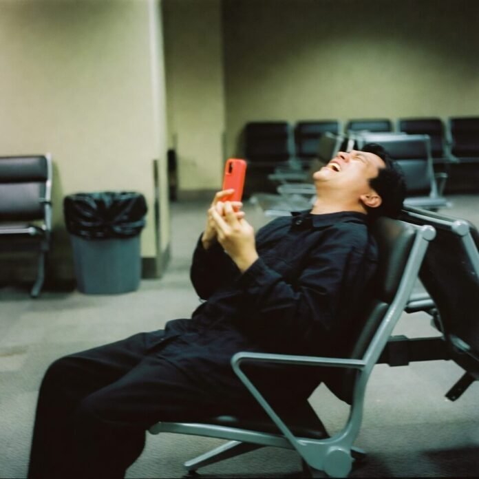 Exhausted traveler collapsed in airport seat taking selfie