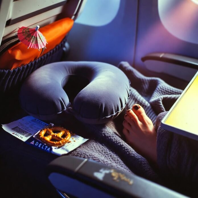 Half-deflated neck pillow, greasy pretzel, bare foot, cocktail umbrella on tray.