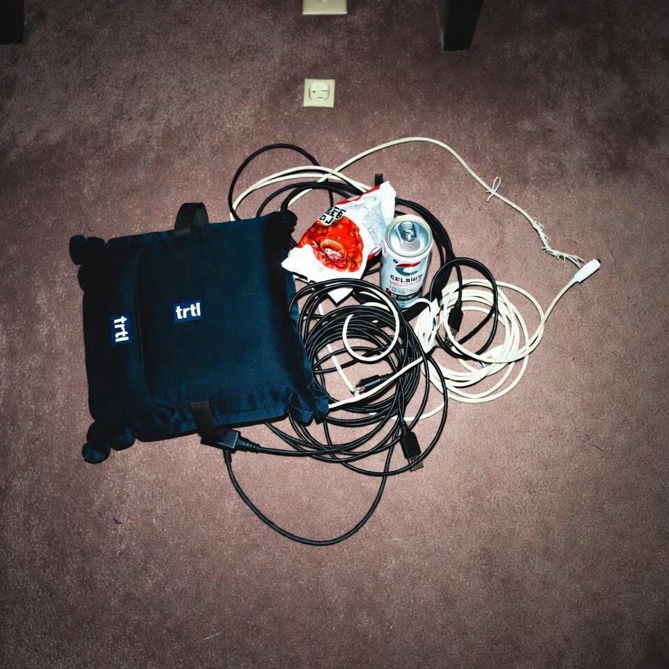 Dumped backpack contents on hotel carpet: deflated pillow, tangled cables, empty can.