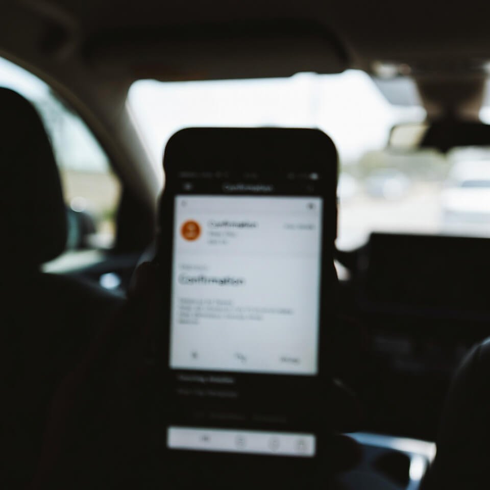 Blurry phone screen showing flight confirmation email in Uber at night