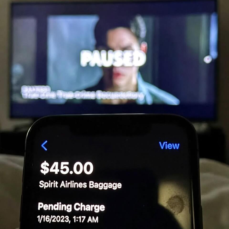 Blurry phone screen showing $45 Spirit baggage fee at night