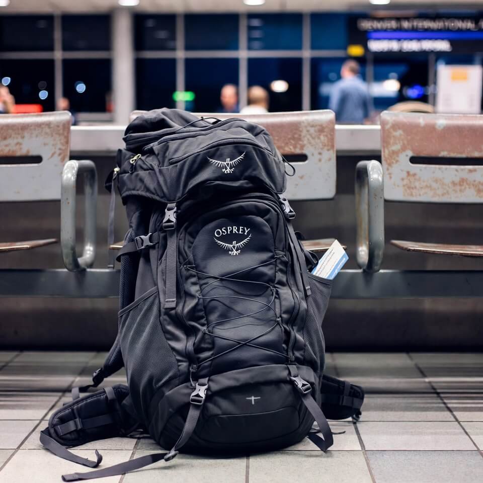 Overstuffed Osprey backpack against rusty bench at Denver airport